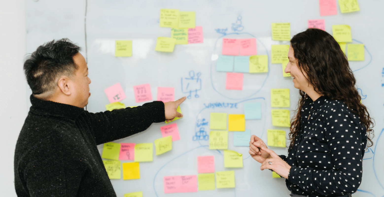 Heidi Ramos and Ryan Ramos in front of whiteboard with post-it notes